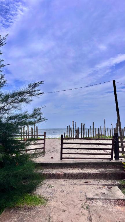 a wooden bench on a beach with the ocean at Emmanuals beach house in Alleppey