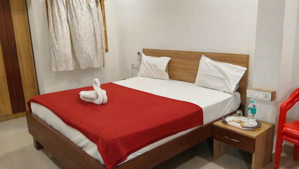 a bed with a white stuffed animal sitting on it at Raya's Inn in Kumbakonam