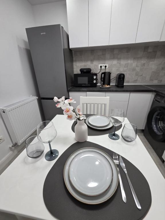 a table with plates and wine glasses on a kitchen counter at Colins Premium Apartments in Giurgiu