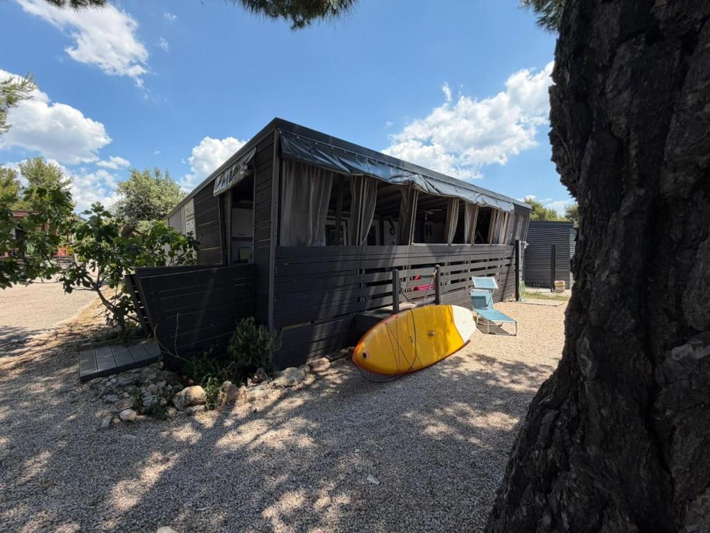a yellow surfboard sitting next to a black building at MOBILE HOME Nikol in Pirovac