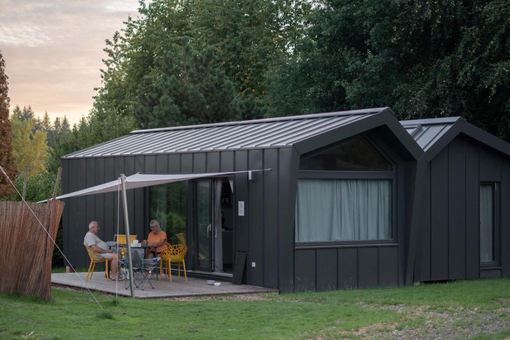 a black shed with two people sitting at a table at Wellnester Tiny Houses in Losheim am See in Losheim