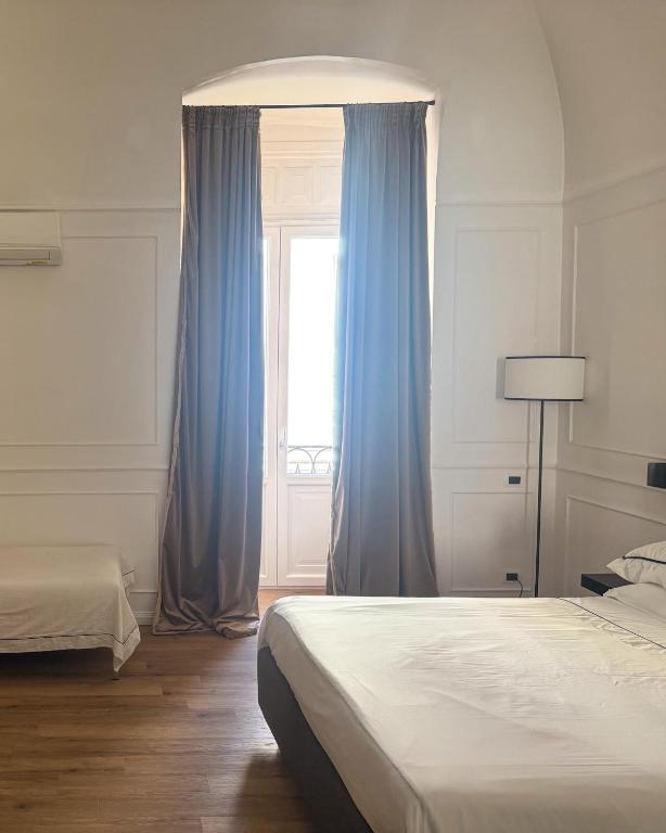 a bedroom with two beds and a window with blue curtains at Borgo Marsala in Trani