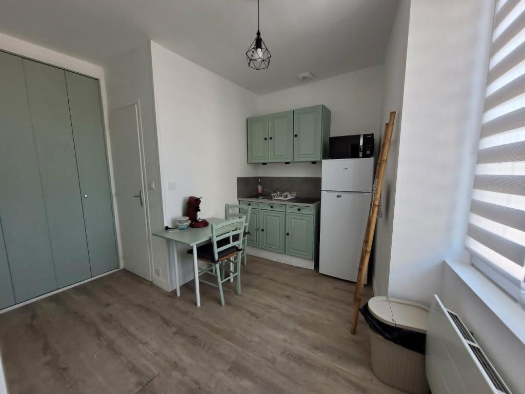 a kitchen with green cabinets and a table and a refrigerator at Appart 1er étage Angers Chalouère in Angers