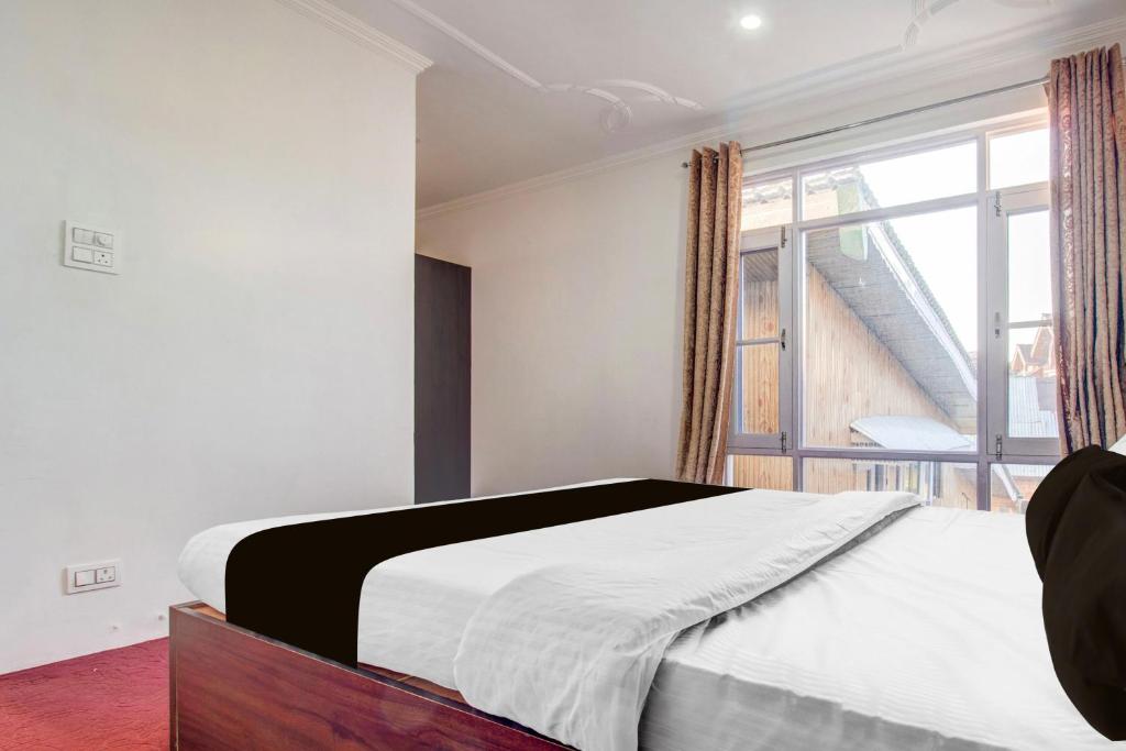 a bedroom with a bed and a large window at Hotel O Wave Inn in Srinagar