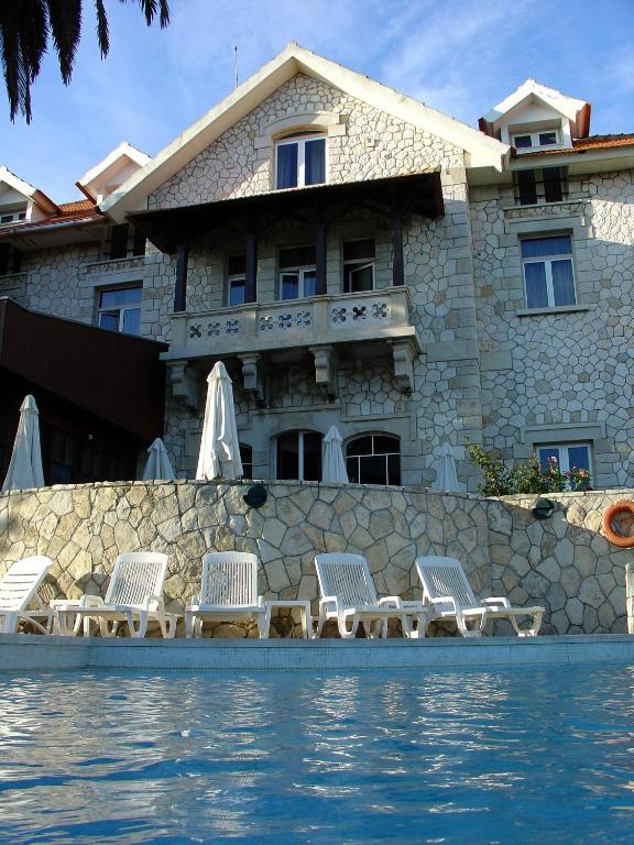 a house with a row of chairs next to a pool at Hotel Solar Palmeiras in Paço de Arcos