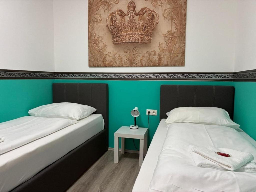 two beds in a room with a crown on the wall at Mariazellerhof Room 015 in Sankt Pölten