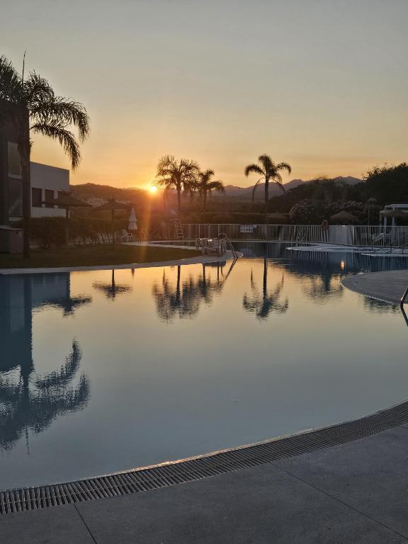 a swimming pool with the sunset in the background at Marina Serena in La Cala de Mijas