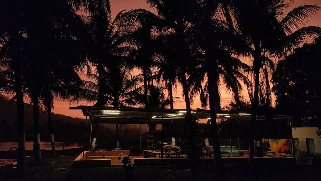 a building with palm trees in front of a sunset at Lake N Trails Exotic Glamping in Khālāpur