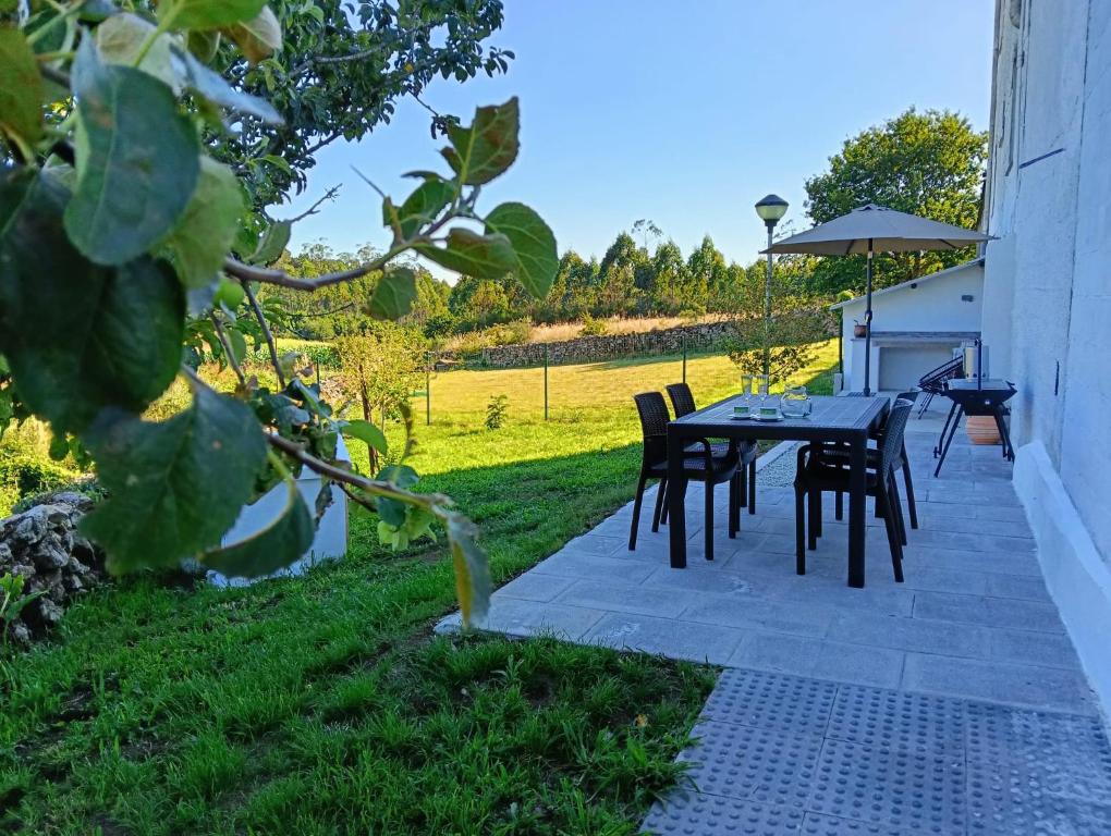 a patio with a table and chairs in the grass at Casa Tamiván in Muxia