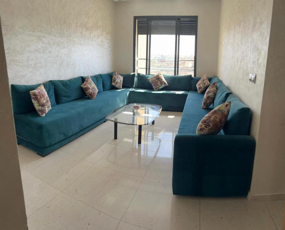 a living room with a blue couch and a glass table at Appart 5min plage, plein centre in Sidi Rahal