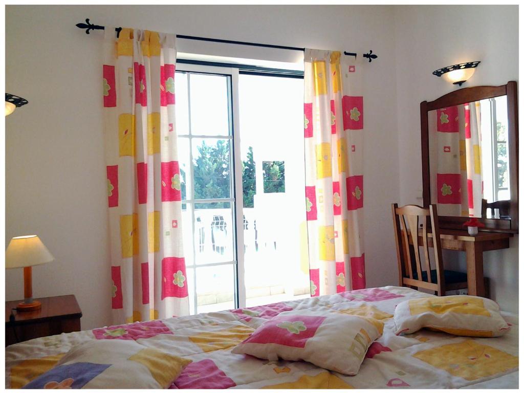 a bedroom with a bed and a large window at Resort Solar Veiguinha in Carvoeiro