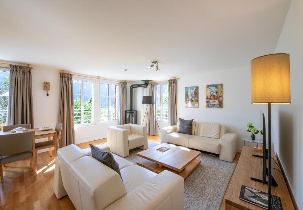 a living room with white furniture and a table at Chalet Mittaghorn Apt 7 in Wengen