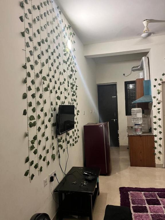 a living room with a wall with leaves on it at Trydan room stay in Chengalpattu