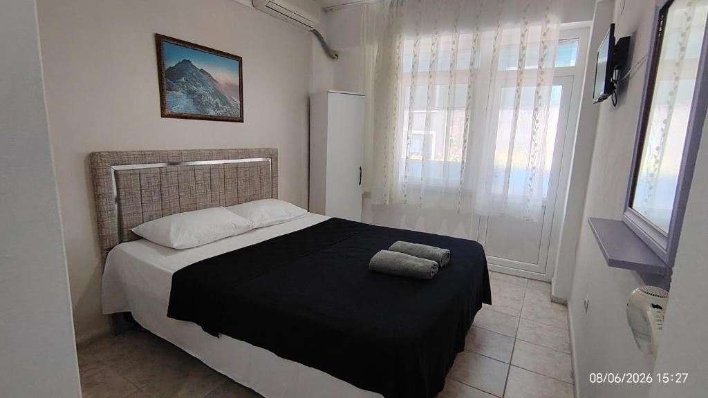 a bedroom with a bed with a black blanket and a window at Avsa BARAN MOTEL apart in Marmara