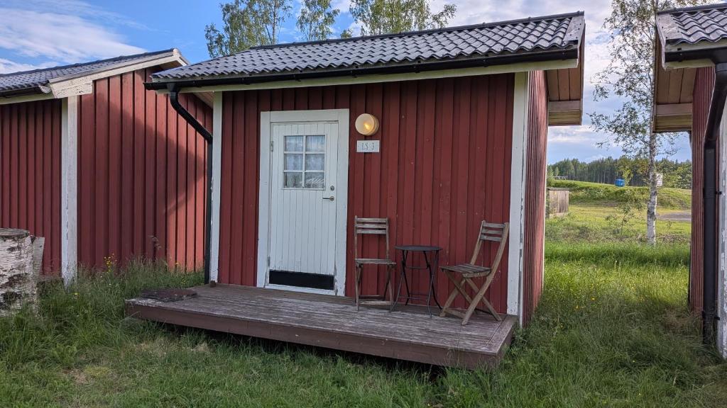 a red shed with two chairs on a wooden porch at Höghedens camping in Älvsbyn