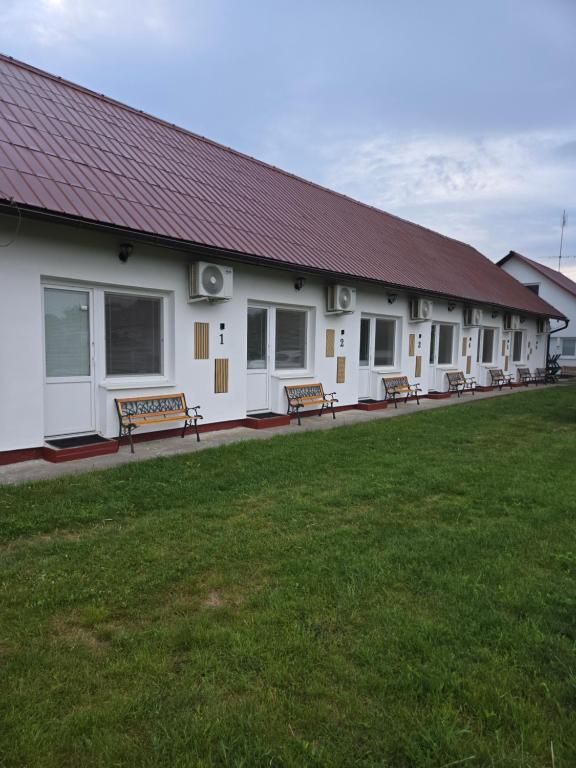 a building with benches in front of a grass field at SALEM apartmany in Radava