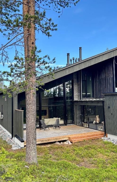 a house with a large deck and a tree at Villa Laponia - Aurora in Äkäslompolo
