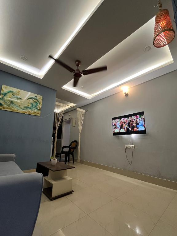 a living room with a ceiling fan and a tv at Pure Bliss 3BHK Stay in Guwahati