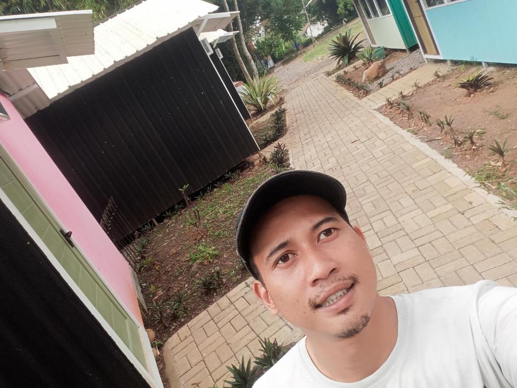 a man wearing a hat standing in front of a house at Hotel in Panenjoan