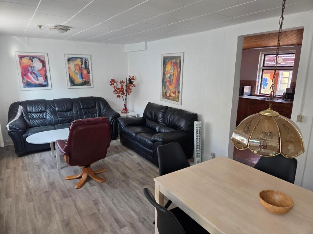 a living room with a black leather couch and a table at Holiday Apartment Rudkøbing in Rudkøbing