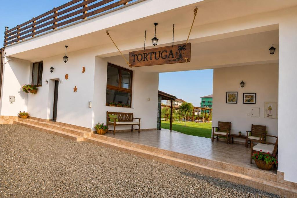 a front porch of a building with benches and a sign at Tortuga in Costinesti