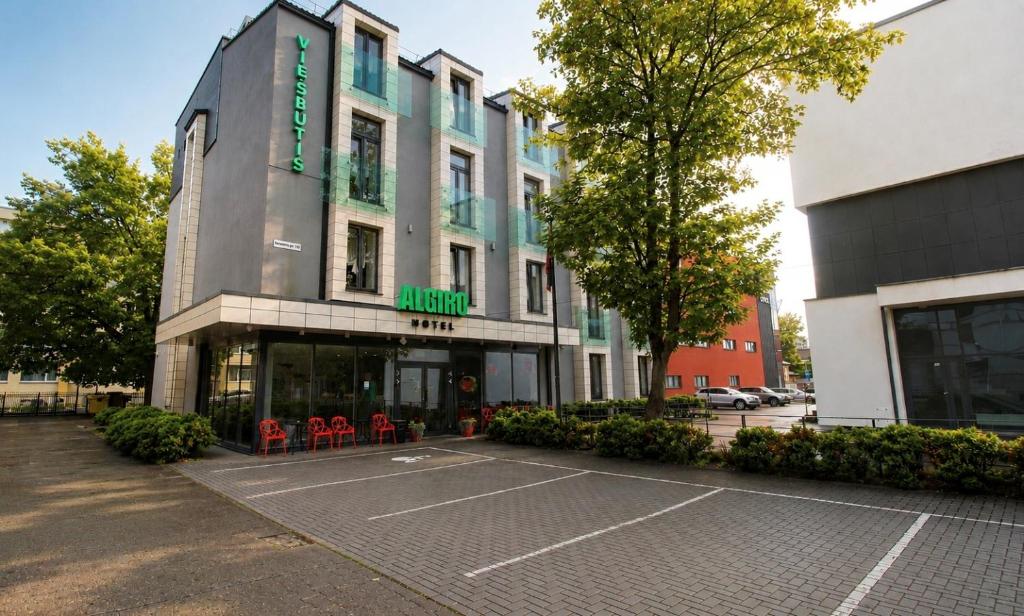 een gebouw met een parkeerplaats ervoor bij Algiro Hotel in Kaunas