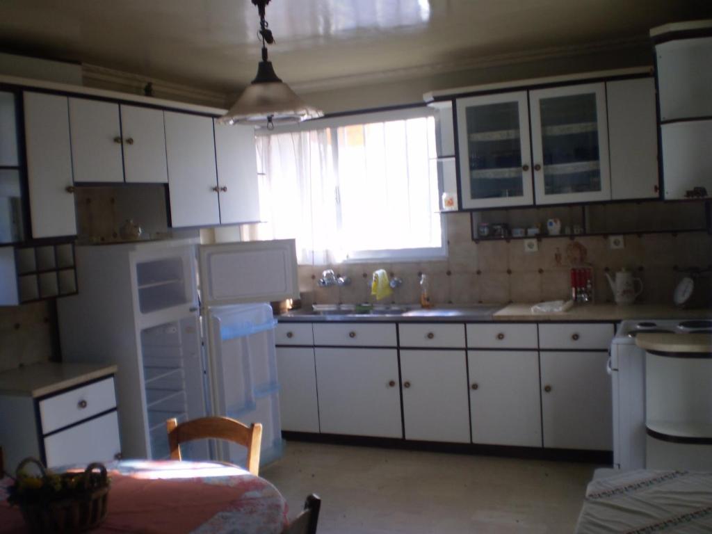 a kitchen with white cabinets and a sink and a window at jenny's apartment in Vrontádos