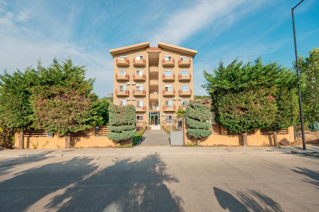 a tall building with trees in front of a street at Serxhio Apartments in Golem