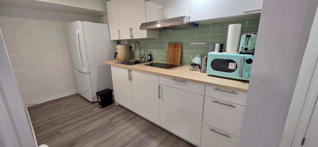 a kitchen with white cabinets and a blue microwave at CozyHaven in St. Catharines