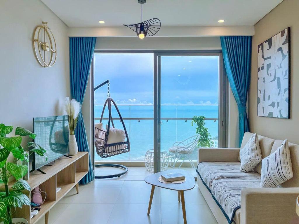 a living room with a couch and a large window at The Song Apartment - Căn Hộ Du Lịch 5 Sao Cạnh Biển Vũng Tàu in Vung Tau