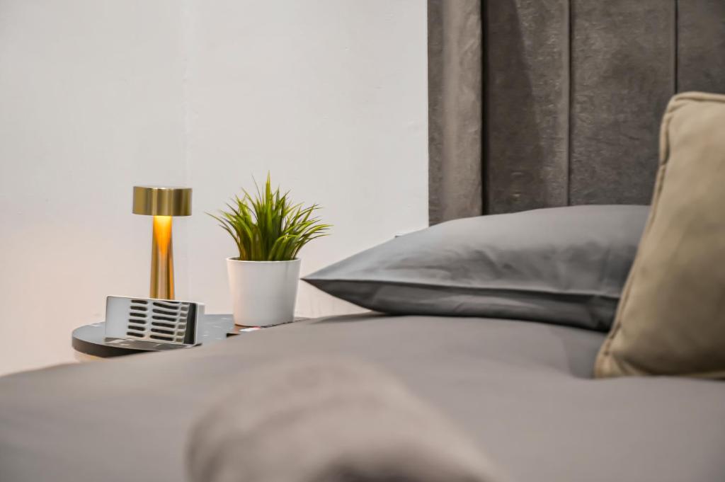 a close up of a bed with a pillow and a lamp at Cosy Rooms in London