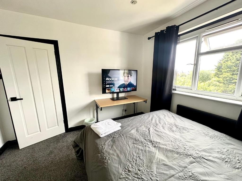 a bedroom with a bed and a tv and a window at Rest & Recover in Wednesbury
