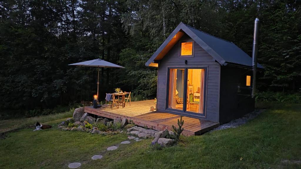 a tiny house with a deck in a yard at Odskocznia bliżej lasu in Korczyna
