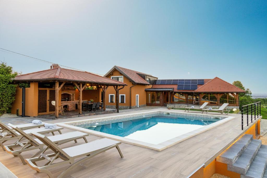 a house with a swimming pool with chairs around it at Holiday Residence Banfi in Štrigova