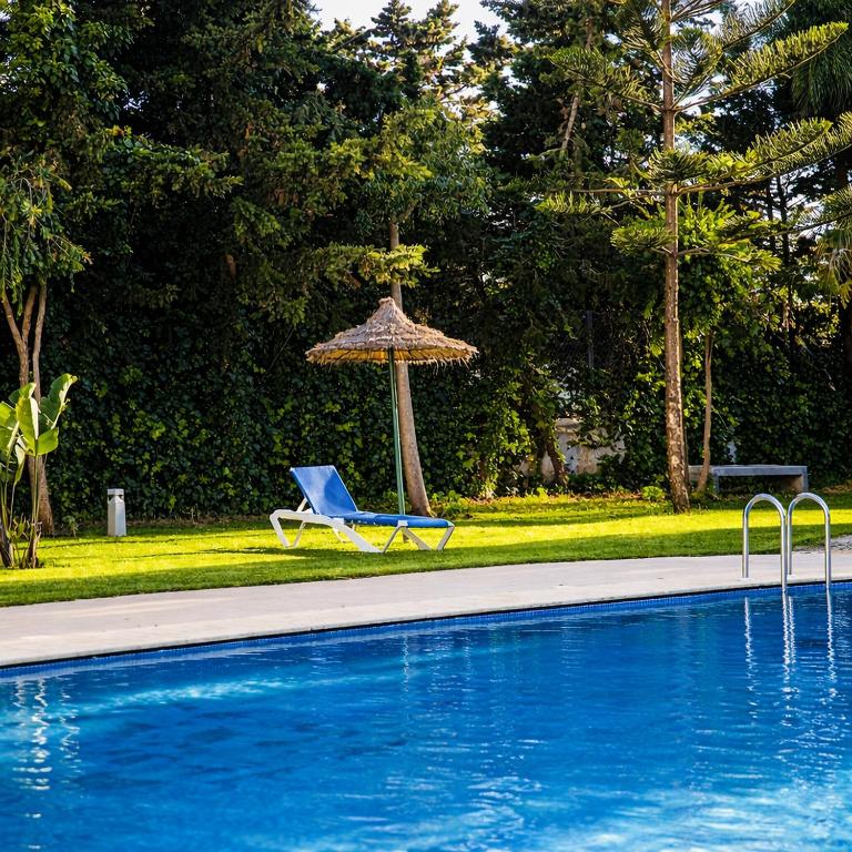 a chair and an umbrella next to a swimming pool at CaboNegro Appart Resort, Piscine, Plage, Détente in Cabo Negro