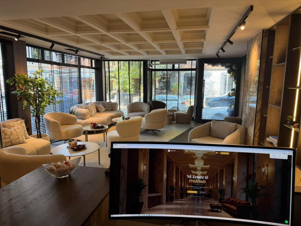 a living room with couches and chairs and a tv at Fron Hotel in Prishtinë