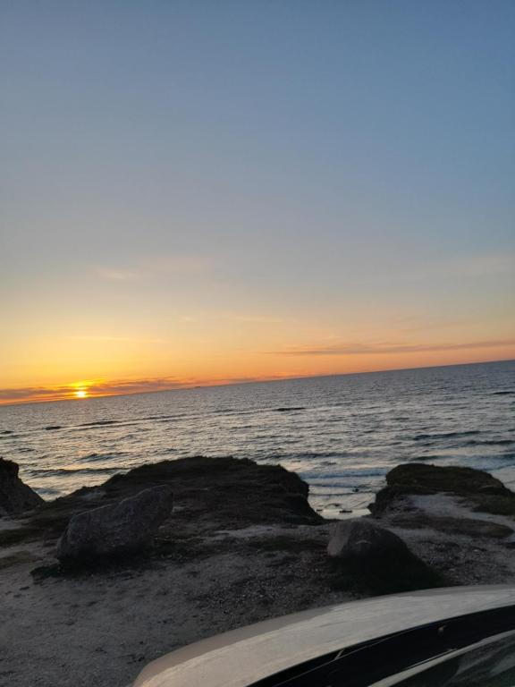 a sunset over the ocean with rocks on the beach at Casa Bonita helt ny lejlighed med eget toilet in Hjørring