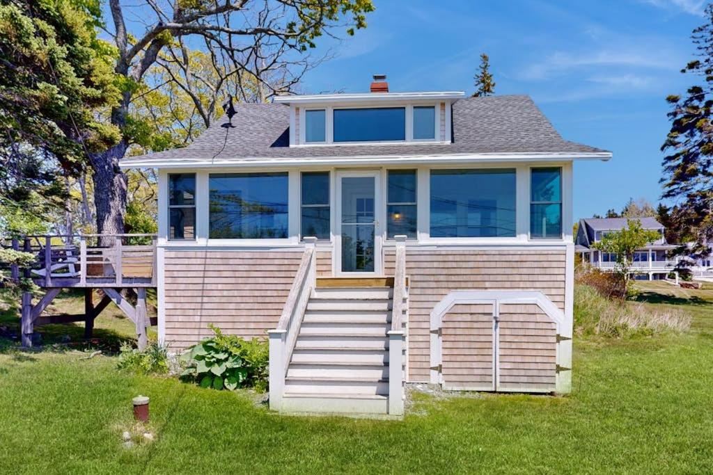 a small house with a porch and stairs in the yard at Ocean Point Colony Home w/ Sunroom & Sweeping Ocean Views, Dog-friendly in East Boothbay