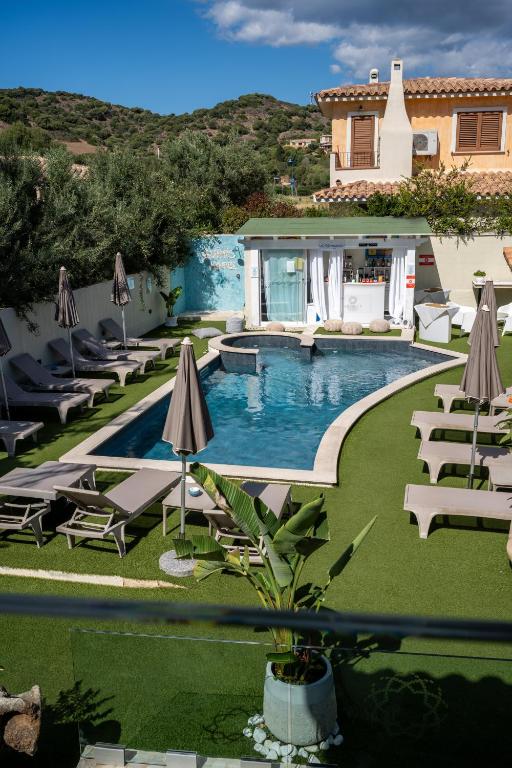 una piscina con sedie e ombrelloni accanto a una casa di Suimi's Hotel a Villasimius