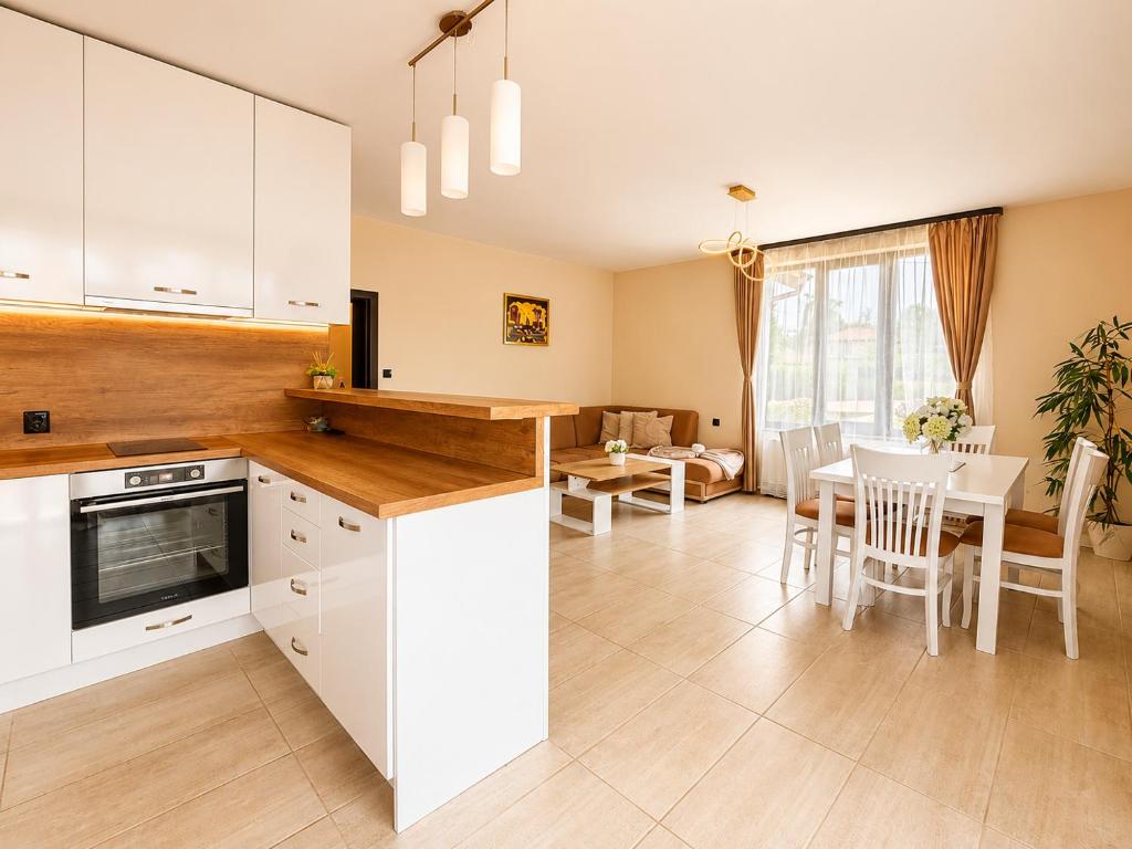 a kitchen and dining room with white cabinets and a table at Къща за гости ЕМ Парадайс in Tserova Koriya