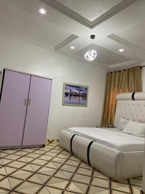 a bedroom with a large bed and a cabinet at Hollysee Hotel & Suites in Baruwa