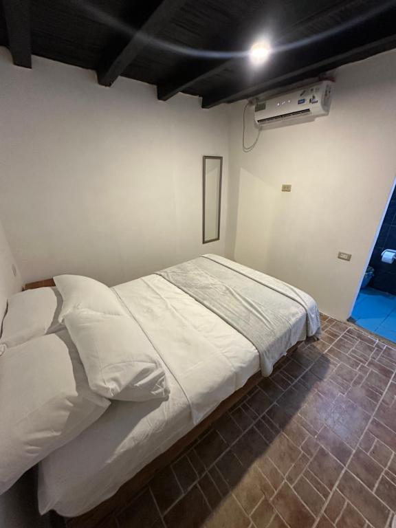 a bedroom with a white bed in a room at HIDDEN HOSTAL MONTANITa in Montañita