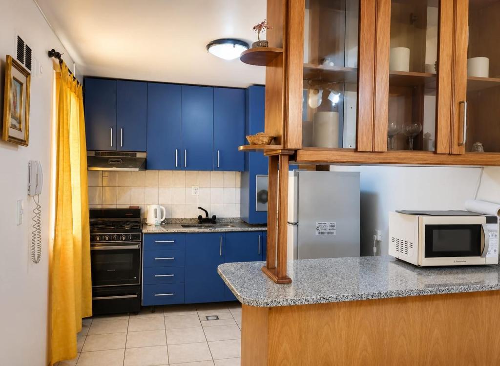 a kitchen with blue cabinets and a microwave at Peatonal y San Martin in Mendoza
