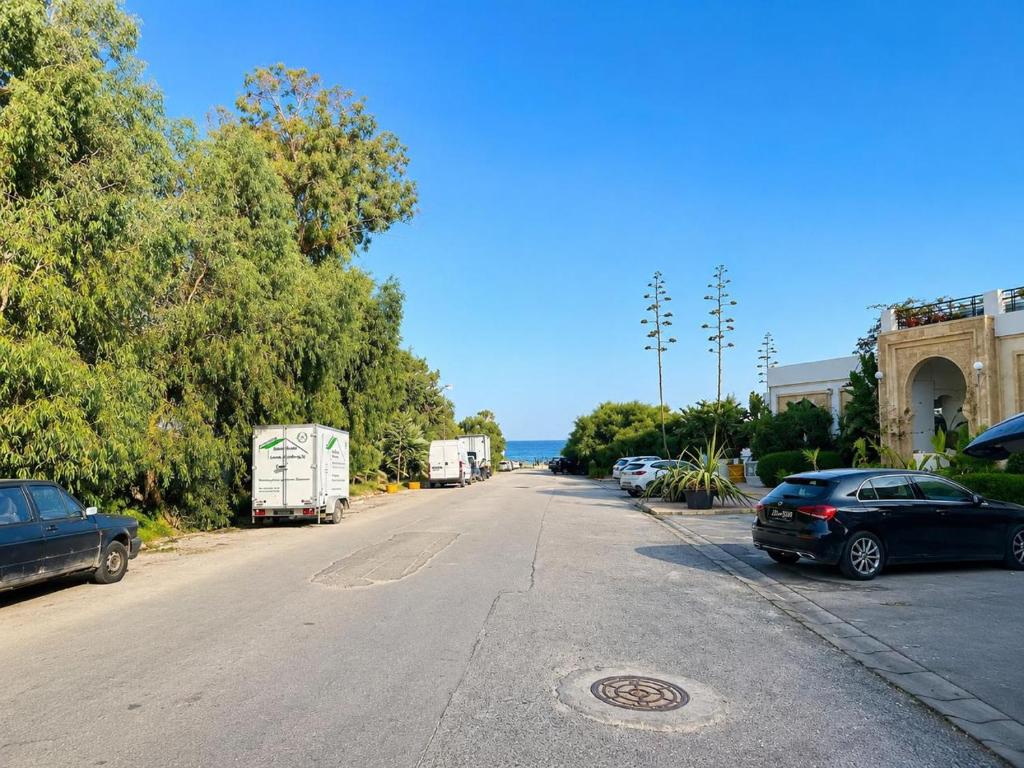 a street with cars parked on the side of the road at Residence Golden Beach au bord de la mer in Bin Rhilouf