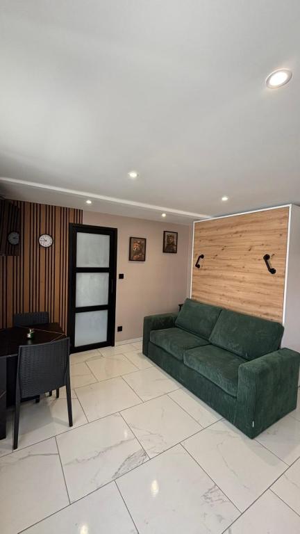 a living room with a green couch and a table at La Parenthèse in Sangatte