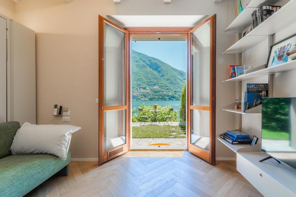 a living room with a large window and a couch at Lakeside Garden Studio in Laglio