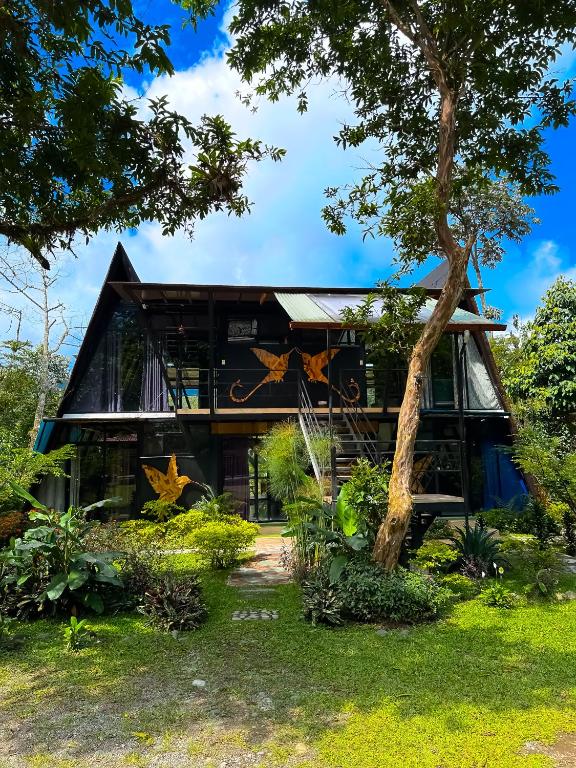 a house with a tree in front of it at Suites Casa ColibrÍ in Mindo