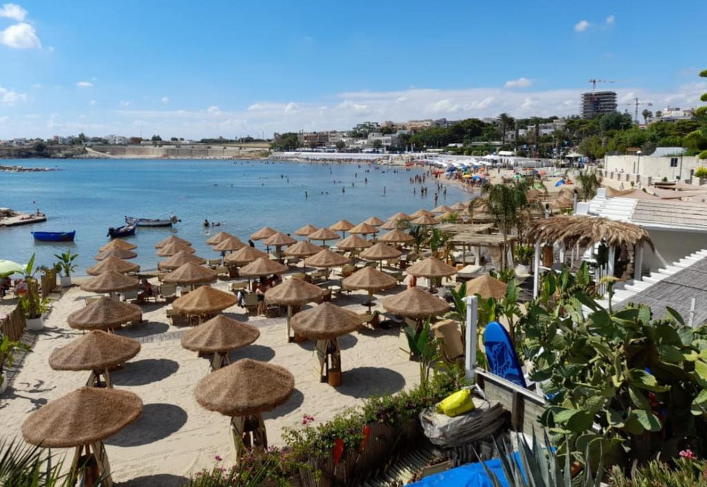 ein Strand mit Sonnenschirmen und Menschen im Wasser in der Unterkunft Levante in Trani