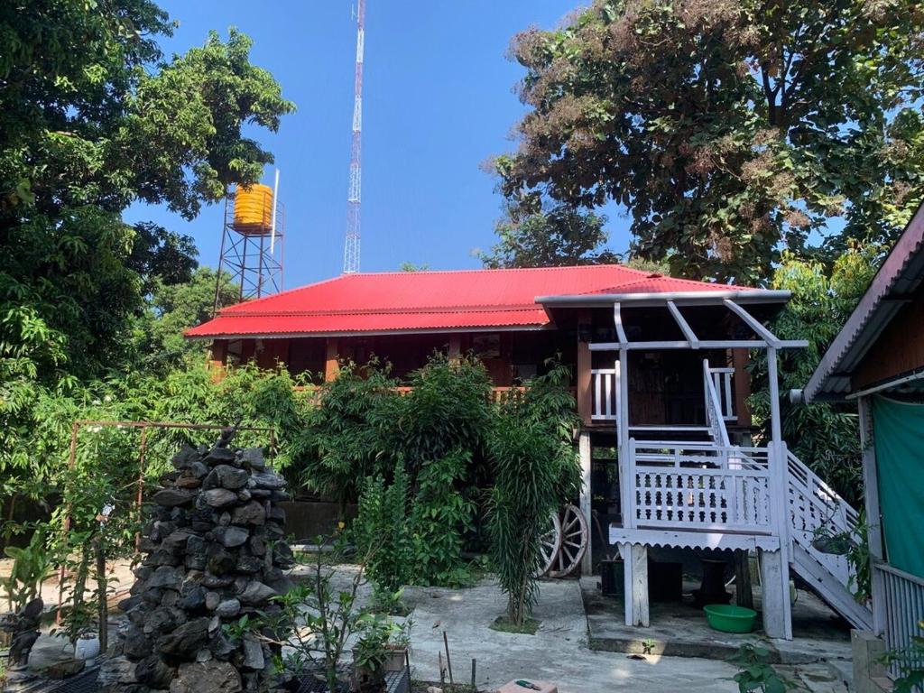 a small house with a red roof and a building at Mangifera Cabin in Kanchanrup in Kanchanpur