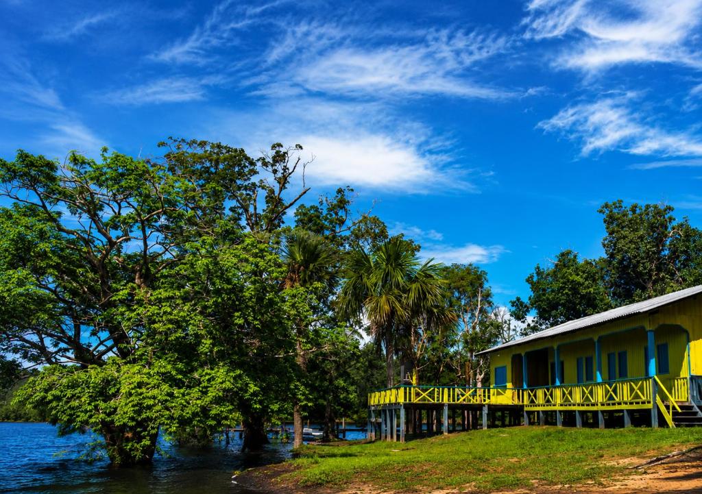 a yellow house next to a body of water at Amazon Anavilhanas Lodge in Aiparuça